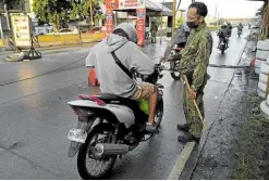  ?? —PHOTO COURTESY OF ZAMBOANGA CITY INFORMATIO­N OFFICE ?? SECURITY CHECK A police officer manning a quarantine checkpoint in Zamboanga City stops a motorist to check his documents as the local government tightens health protocols due to a recent surge in COVID-19 infections.