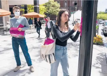  ?? EVAN VUCCI/AP ?? Students put up posters calling for student loan debt forgivenes­s on Friday near the White House.