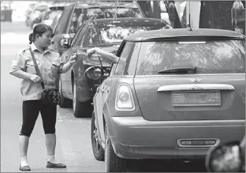  ?? FENG YONGBIN / CHINA DAILY ?? A warden collects a parking fee from a driver in Beijing.