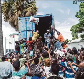  ?? AFP PIC ?? A man throwing a bag of rice into a crowd of earthquake victims at the ‘4 Chemins’ crossroads in Les Cayes on Friday.