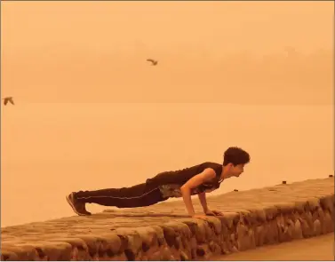  ?? REUTERS ?? A man exercises amidst haze and dust near Sukhna Lake in Chandigarh on Friday.