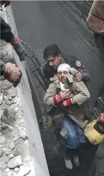  ??  ?? The Syria Civil Defence helps an unconsciou­s woman from a shelter in Douma. Photo: Reuters