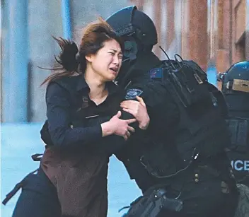  ?? Picture: AP PHOTO/ROB GRIFFITH ?? A hostage runs to armed tactical response police officers for safety after she escaped from the Lindt Cafe siege at Sydney’s Martin Place in 2014