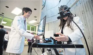  ??  ?? Yau and Anysia Unick, also an optometry student at the University of Waterloo, use a virtual reality system in a new training lab.
