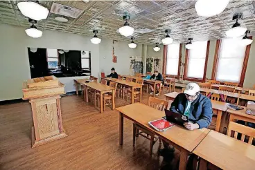  ?? [PHOTOS BY STEVE GOOCH, THE OKLAHOMAN] ?? Students wait for a class to start in the historical classroom inside Old North at the University of Central Oklahoma. The podium was constructe­d from timber removed from the original building.