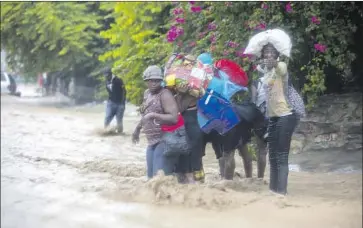  ?? Dieu Nalio Chery Associated Press ?? HAITIANS try to cross a street in Port-au-Prince. Tropical Storm Laura flooded swaths of Haiti and the Dominican Republic. As Hurricane Marco churns toward Louisiana, Laura may follow at hurricane strength.