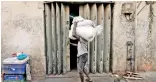  ??  ?? A labourer tries to open a door at a storeroom, as he carries sacks of rice near a main market in Colombo. (Reuters photo)