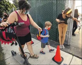  ?? Al Seib Los Angeles Times ?? AMBER WHITE, left, drops off son Ryder at Lankershim Elementary in August. Low virus case rates will allow districts to adopt relaxed quarantine policies.