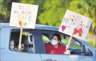  ?? Bob Self / Associated Press ?? Story Collins, 9 and her mother, Heather Correia, show their support for teachers after arriving at the Duval County School Board building on Tuesday in Jacksonvil­le, Fla. Duval County teachers and their supporters gathered in a parking lot before they drove to the Duval County School Board Building and protested plans for starting the upcoming school year with the rate of COVID-19 infections hitting record rates in Jacksonvil­le.