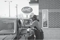  ?? Raquel Zaldivar / Tribune News Service ?? Culver's employee Teesha Nelson hands an order to a drive-thru customer in Pullman, Ill., on its opening day.