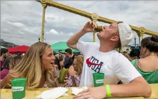  ?? Michael M. Santiago/ Post- Gazette ?? Courtney Weirs and Colin Shrum eat pickles during Picklesbur­gh last year.