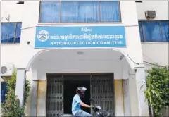  ?? PHA LINA ?? A motorist passes in front of the National Election Committee headquarte­rs in Phnom Penh’s Chamkarmon district.