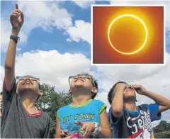  ?? AFP ?? Children in Manila yesterday watch the moon move in front of the sun in a rare ‘ring of fire’ solar eclipse, inset.