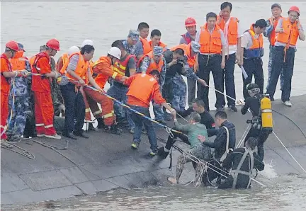  ?? AFP/GETTY IMAGES ?? A survivor is rescued by divers from the Eastern Star cruise ship that capsized in the Yangtze River in central China. At least 15 people were brought to safety as divers raced to find survivors on Tuesday. More than 450 people, most of them elderly,...