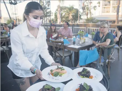  ?? PHOTOS BY DREW A. KELLEY ?? Jocelyn Silva serves dinner entrees at the DAOU Sidestage Experience during the BeachLife music festival in Redondo Beach on Friday.