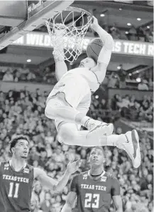  ?? Elise Amendola / Associated Press ?? Villanova’s Donte DiVincenzo hangs on the rim after dunking over Texas Tech’s Zach Smith, left, and Jarrett Culver, right, during the second half Sunday in Boston.