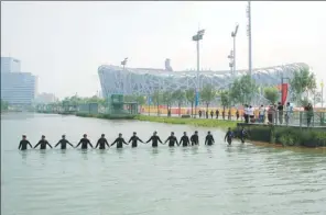  ??  ?? The squad’s divers conduct security checks in the waterway beside Beijing’s National Stadium.
