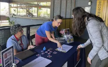  ?? Anita Snow/Associated Press ?? Volunteer signature gatherers Judy Robbins, left, and Lara Cerri, center, watch outside a bookstore as voter Grace Harders prepares to sign a petition that aims to enshrine the right to abortion in Arizona, Wednesday in Phoenix.