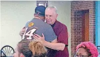  ??  ?? A camper gives the Rev. Paul Zahler a hug during lunch at the National Institute on Developmen­tal Delays at St. Gregory’s University in Shawnee.