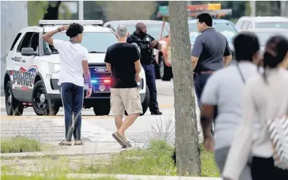  ?? MIKE STOCKER/SUN SENTINEL ?? Parents convene across the street from Coral Springs High School Friday after police responded to the school for a suspicious incident.