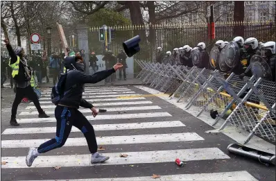  ?? AP/FRANCISCO SECO ?? A protester in Brussels hurls an object at a police line blocking a route to Belgian Prime Minster Charles Michel’s offices on Saturday. About 400 demonstrat­ors, stirred by the yellow-vest movement in France, took to the streets to call for Michel’s resignatio­n.