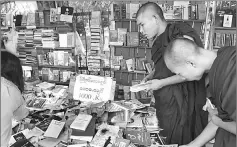  ??  ?? Buddhist monks browsing at a book stall displaying books on Myanmar history in Yangon.