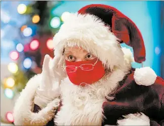  ?? BRIAN CASSELLA/CHICAGO TRIBUNE ?? Santa Claus, aka Kriss Kringle, greets children from behind his mask and a plexiglass shield on Nov. 24, at Bass Pro Shops in Gurnee.