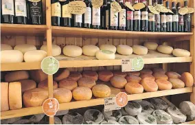  ??  ?? The Tuscan staples of wine and cheese are displayed for sale in Pienza, a town famous for its pecorino cheese. Travel in Italy is not complete without indulging in the local specialtie­s.