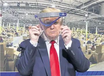  ?? REUTERS ?? Donald Trump holds up a protective face shield during a tour of the Ford Rawsonvill­e Components Plant that is manufactur­ing ventilator­s, masks and other medical supplies during the Covid-19 pandemic in Ypsilanti, Michigan, on Thursday.