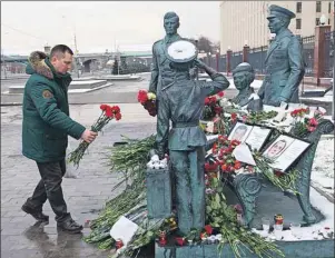  ?? AP PHOTO ?? A man puts flowers aside photos of Lt. Col. Oleg Peshkov and sailor Alexander Pozynich at a monument outside Russian Army General Staff headquarte­rs in Moscow, Russia, Thursday. Peshkov was a pilot of Russian Su-24, which was shot down by Turkish air...