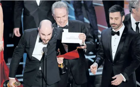  ?? CHRIS PIZZELLO/THE ASSOCIATED PRESS ?? In this Feb. 26, 2017, file photo, Jordan Horowitz, producer of La La Land, left, shows the envelope revealing Moonlight as the true winner of best picture at the Oscars, in Los Angeles, as presenter Warren Beatty and host Jimmy Kimmel, right, look on....