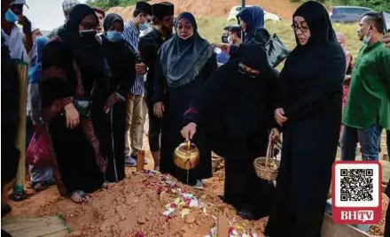  ?? (Foto BERNAMA) ?? Norzizi (kanan) bersama keluarga menyiram air mawar di atas pusara Allahyarha­m Zulkifli di Tanah Perkuburan Islam Ukay Perdana, semalam.