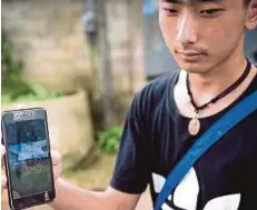  ??  ?? Thananchai Saengtan showing a photo of his missing friends on his handphone near Tham Luang cave yesterday.