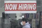  ?? JEFF CHIU — THE ASSOCIATED PRESS FILE ?? A manwearing a mask walks under a “Now Hiring” sign at a CVS Pharmacy in San Francisco.