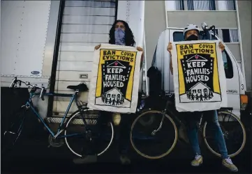  ?? ANNE WERNIKOFF FOR CALMATTERS ?? Galen Mancino, left, and Betsy Kinsey, hold up banners during a housing justice demonstrat­ion in the Adams Point neighborho­od of Oakland on Dec. 5.