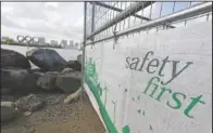  ?? (AP/Eugene Hoshiko) ?? A constructi­on fence featuring the words “Safety First” with a backdrop of the Olympic rings floating in the water in the Odaiba section in Tokyo. .