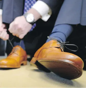  ?? TROY FLEECE ?? Finance Minister Kevin Doherty tries on a new pair of shoes in Regina on Tuesday in a pre-budget ritual ahead of Wednesday’s provincial budget. Sask. residents are bracing for changes in health and education.
