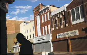  ?? Patrick Semansky / Associated Press ?? A man walks past vacant storefront­s at the Old Town Mall in Baltimore.