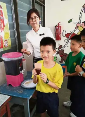  ??  ?? Herbal healing: A teacher giving out herbal tea to the pupils of SJK (C) Poay Wah to drink.