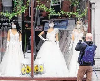  ?? PHOTO: BRIAN LAWLESS ?? Masked up: A man takes a picture of the window display at a Dublin bridal boutique.