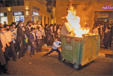  ?? (AP/Oded Balilty) ?? Ultra-Orthodox Jews burn a dumpster Monday during a protest against a coronaviru­s lockdown for their neighborho­od in Jerusalem.