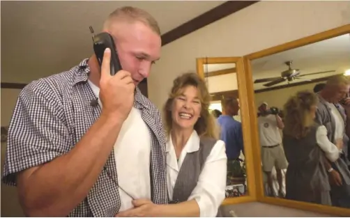  ?? SUN-TIMES ?? Brian Urlacher gets a hug from his mother, Lavoyda, while taking a call from the Bears, who drafted him in the first round in 2000.