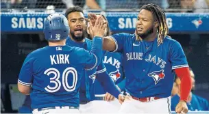  ?? COLE BURSTON GETTY IMAGES ?? Alejandro Kirk is greeted by Vladimir Guerrero Jr. after scoring in the fourth inning. Guerrero later hit his 45th home run, first in the majors and one more than his father had in his best season.