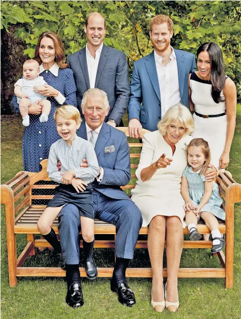  ??  ?? Prince Charles nurses his elder grandson, Prince George, as he poses for an official family portrait in the gardens of Clarence House to mark his 70th birthday