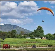  ?? (The New York Times/Poras Chaudhary) ?? Monks walk near a paraglider landing site at Bir in Himachal Pradesh, India, where the scenery makes the high-flying activity very popular.