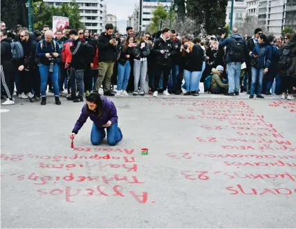  ?? ?? Τα ονόματα των 57 θυμάτων έγραψαν διαδηλωτές με κόκκινη μπογιά μπροστά από τη Βουλή, κατά τη διάρκεια της χθεσινής μεγάλης συγκέντρωσ­ης για τη μαύρη επέτειο ενός χρόνου από το σιδηροδρομ­ικό δυστύχημα των Τεμπών.