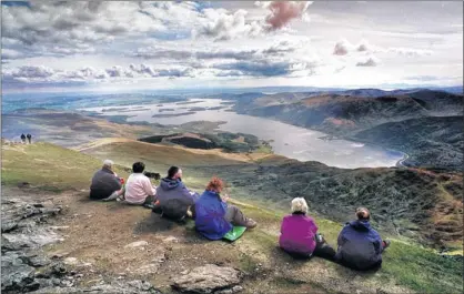  ??  ?? HIGH AMBITION: Walkers take a break to enjoy the magnificen­t view from the summit of Ben Lomond in the national park. Picture: Colin Mearns