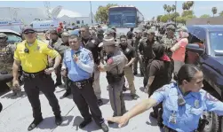  ?? AP PHOTO ?? CLEARING A PATH: Officers secure the street to allow a bus with immigrant children aboard to move after protesters blocked it.