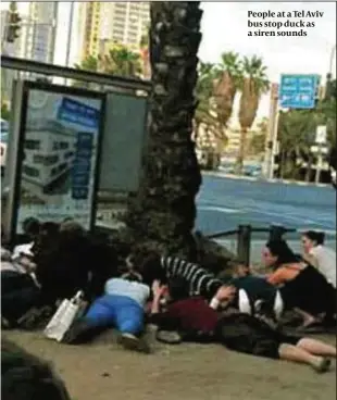  ?? PHOTO: TWITTER/MAAYAN SIMHONI ?? People at a Tel Aviv bus stop duck as a siren sounds