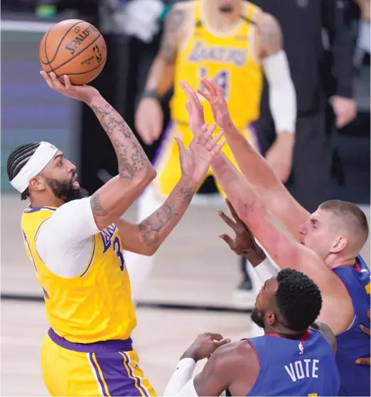  ?? AP ?? The Lakers’ Anthony Davis (37 points and 10 rebounds) shoots over the Nuggets’ Paul Millsap (bottom front) and Nikola Jokic (right) during the series opener Friday.